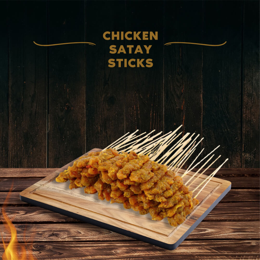 A wooden board filled with a large pile of raw chicken satay sticks, ready to be cooked.